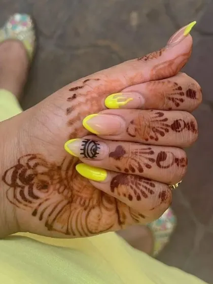 A unique combination of a vibrant yellow French tip and custom hand-painted evil eye art on an almond-shaped nail extension.