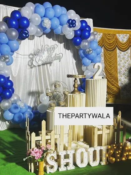A simple and elegant ring decoration with blue and white balloons against a yellow curtain. The light-up name sign adds a personal touch.
