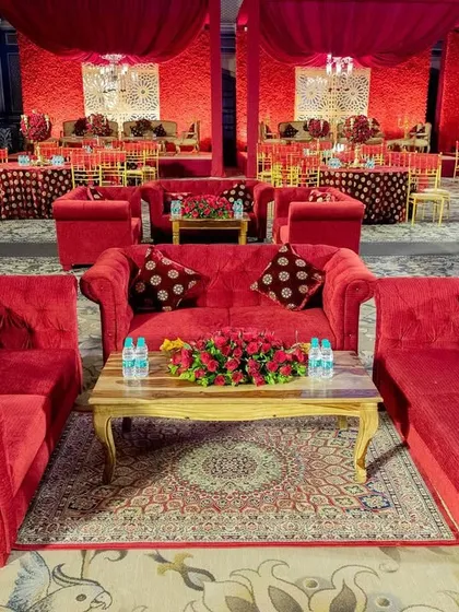 The lounge area for a red-themed wedding, with comfortable red sofas and traditional rugs creating a warm and inviting space for guests.