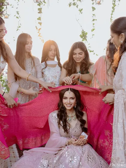 A beautiful traditional moment from the roka ceremony. The bride surrounded by her loved ones under a vibrant pink dupatta is a classic shot, full of color and happiness.