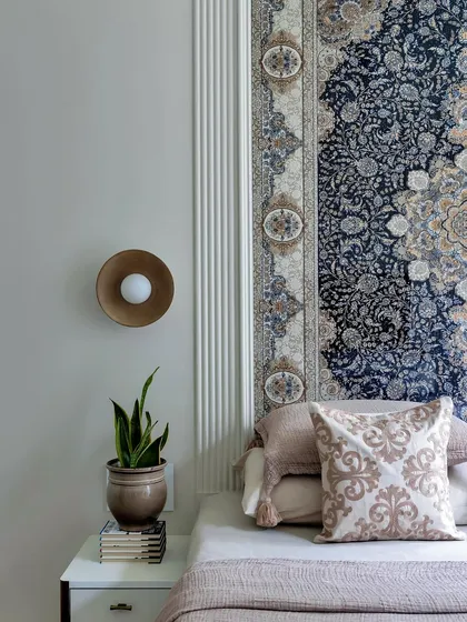 A closer look at the tapestry headboard, showing the intricate details of the pattern. The simple bedding and modern sconce ensure the headboard remains the star of the show.