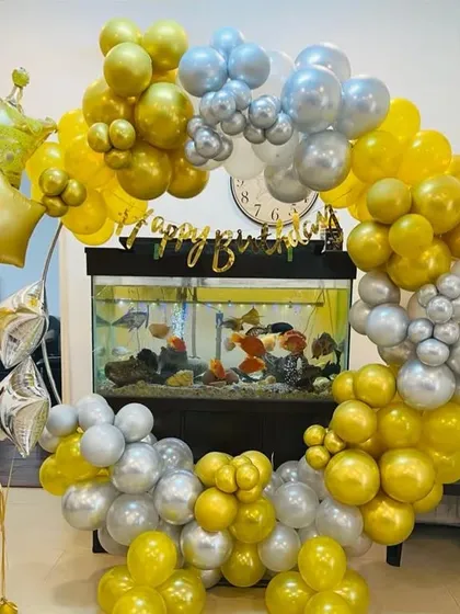 I can even incorporate existing home features into the decor. Here, I built a gold and silver balloon ring around a fish tank, creating a unique and personalized birthday backdrop.