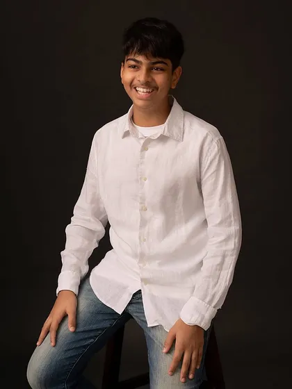A portrait of my own son, his bright, genuine smile captured against a classic dark background. I believe in letting kids be themselves, and sometimes that means just letting them laugh.