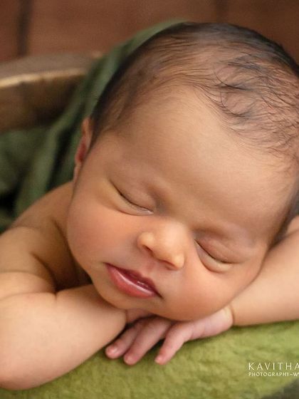 Six-day-new Anshu in the chin-on-hands pose. The rich green wrap and rustic bucket create a beautiful, earthy portrait that feels both classic and natural.