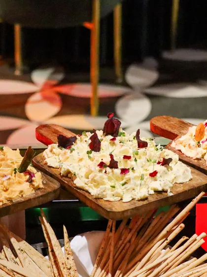 A trio of our signature dips, including a vibrant beetroot hummus, served on wooden boards with a generous side of breadsticks.