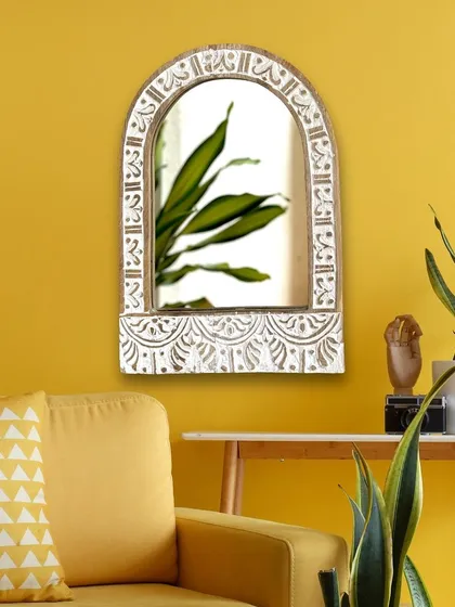 See how this jharokha-inspired arched mirror transforms a simple wall into a statement. The distressed white finish on the hand-carved mango wood provides a beautiful contrast against a vibrant color, making it a perfect focal point for a living room or entryway.