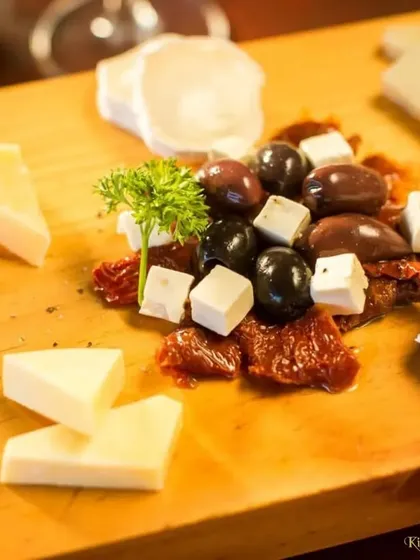 A deconstructed cheese board focusing on high-quality ingredients. This platter features blue cheese, feta, olives, and sun-dried tomatoes, perfect for creating your own flavour combinations.