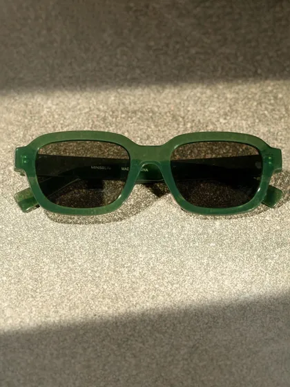 A close-up of the Miniso sunglasses, focusing on the texture and color of the frames under dramatic lighting. This detail shot is great for product pages.