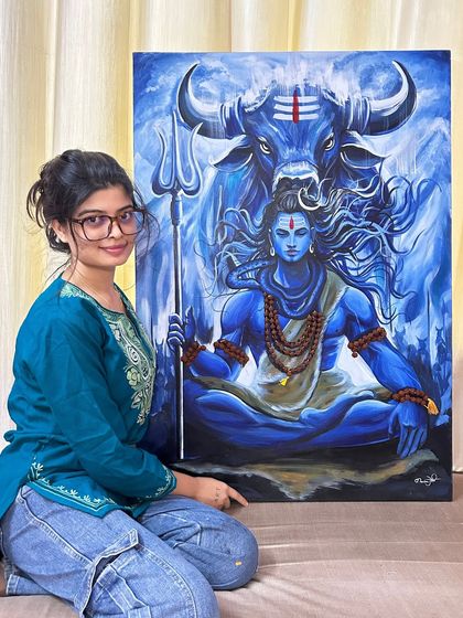 A photo of me with my completed Mahadev canvas painting. It brings me so much joy to create a piece that feels so powerful and to see the vision come to life after many hours of work.