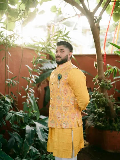 A stylish shot of the groom, showcasing his Haldi attire and the peacock feather detail.