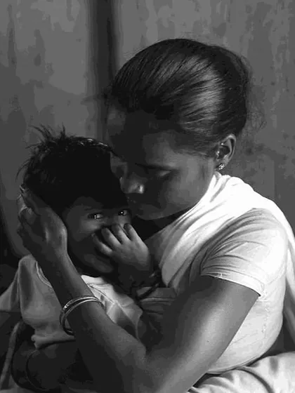 A tender moment between a mother and child, captured by Sudharak Olwe. The black and white format emphasizes the emotion and stark reality of the families' experiences at Nutrition Rehabilitation Centres.