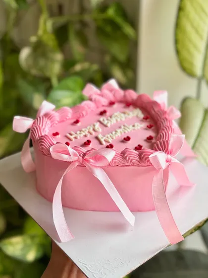 A side view of the pink birthday heart cake, showing how the ribbons cascade down the sides for a soft and celebratory balletcore look.