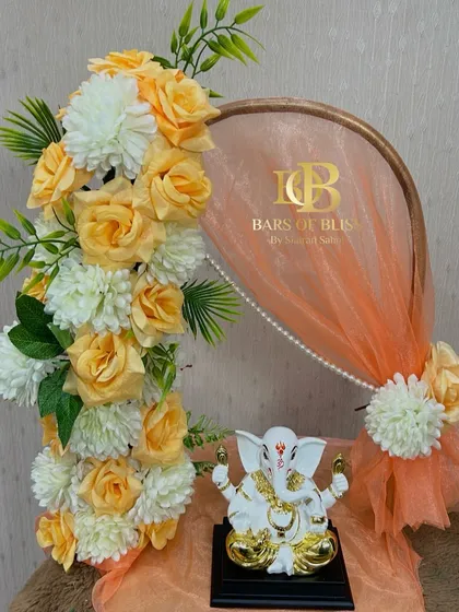 An elegant and modern take on festive decor. This setup features a hoop decorated with peach-colored roses and an organza drape, creating a soft and beautiful backdrop for the Ganpati idol.