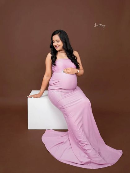 A simple yet elegant portrait of a mother-to-be in a lavender gown. The solid brown background makes the color of the dress pop, highlighting her beautiful silhouette.