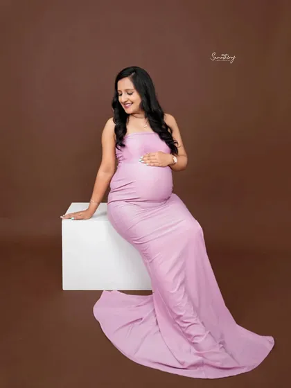 A simple yet elegant portrait of a mother-to-be in a lavender gown. The solid brown background makes the color of the dress pop, highlighting her beautiful silhouette.