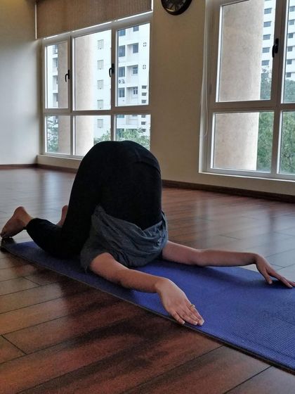 A student in Karnapidasana, a deep forward bend that calms the nervous system. This image is a reminder that progress is a journey, and every pose tells a story of growth.