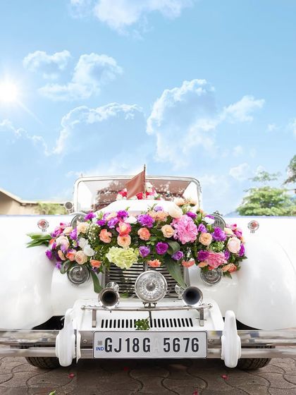 A vintage car decorated with a lavish arrangement of colorful flowers. This makes for a stunning prop for the couple's photos and a grand entry or exit vehicle.
