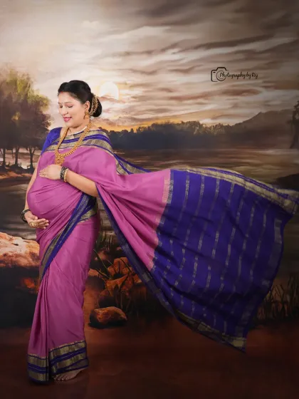 A fine-art studio portrait with the mother-to-be in a magenta saree, with the fabric flowing beautifully against a painted backdrop.