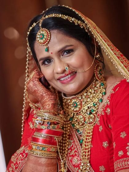 The quintessential bridal pose. This bride looks stunning in a heavy, multi-layered Kundan set with green and red accents, perfect for a traditional wedding.
