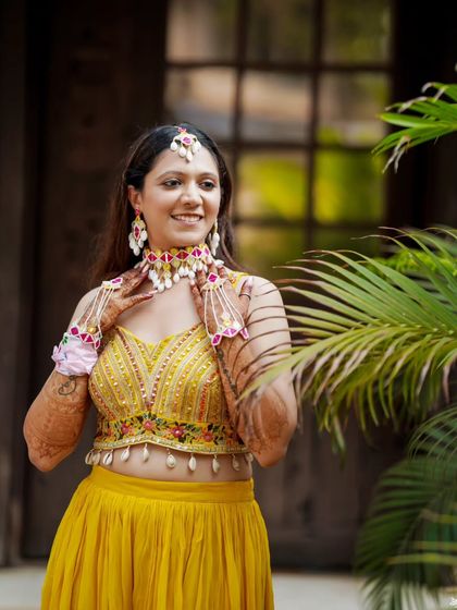 The bride, radiant in yellow, adorned with floral jewelry for her Haldi ceremony.