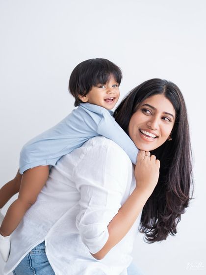 A mother giving her son a piggyback ride, both of them laughing.