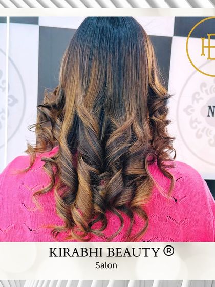 A close-up of these beautifully styled curls after a color treatment. The highlights add so much dimension and shine to the hair.