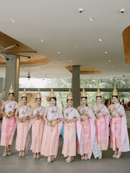 A lineup of elegant Thai dancers in traditional pink and white attire, ready to welcome guests. Their grace and beauty add an authentic touch of Thai culture to the wedding.