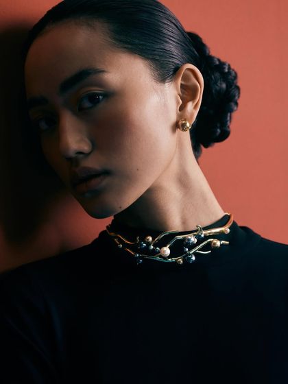 A close-up portrait highlighting the delicate choker. The model's pose and expression are soft yet confident, reflecting the brand's aesthetic.