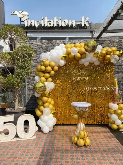 Celebrating a 50th birthday in style with this outdoor setup. I used a brilliant gold sequin wall, a gold and white balloon arch with disco ball accents, and large marquee numbers to mark the golden milestone.