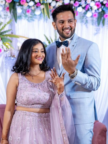 That "we're engaged!" feeling. A joyful shot of the couple showing off their new rings to the camera, with the beautiful floral stage decor in the background.