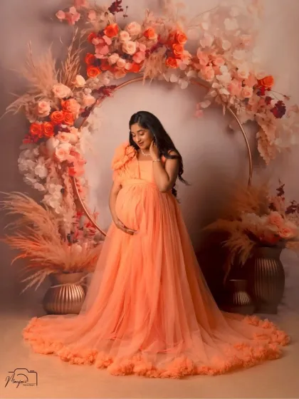 A gentle and serene pose, with the mama-to-be looking down at her bump. The floral ring creates a perfect frame for this intimate moment.