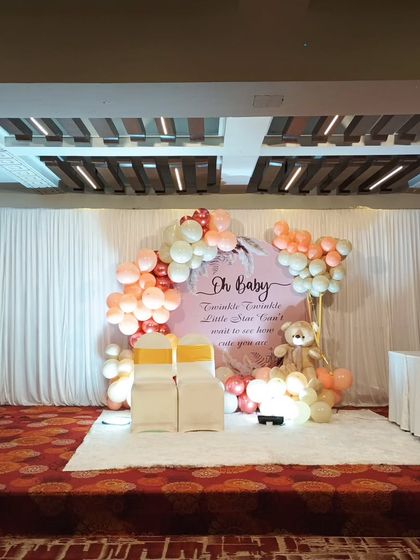 A wide view of the baby shower stage in a banquet hall, featuring our elegant "Oh Baby" backdrop and seating for the parents-to-be.