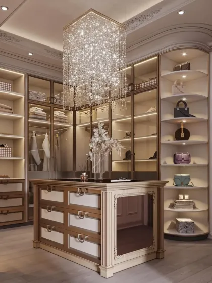 I design walk-in closets that are both a sanctuary and a statement. This space features a stunning crystal chandelier, custom glass-front cabinetry with internal lighting to display accessories, and a central island with organized drawer storage for a truly luxurious dressing experience.