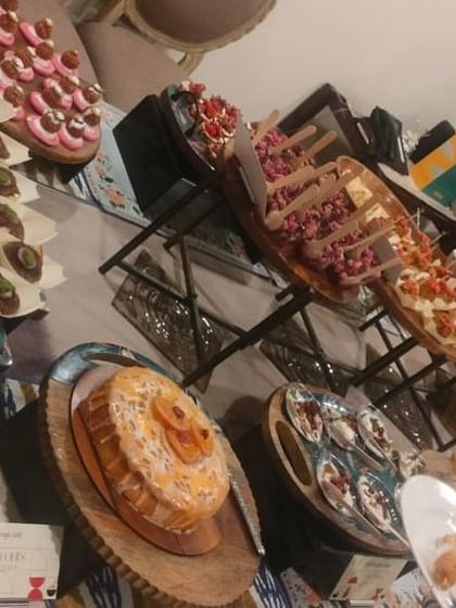 An angled view of the dessert section of a high-tea party. It features a variety of cakes, tarts, and other sweet treats to delight your guests.