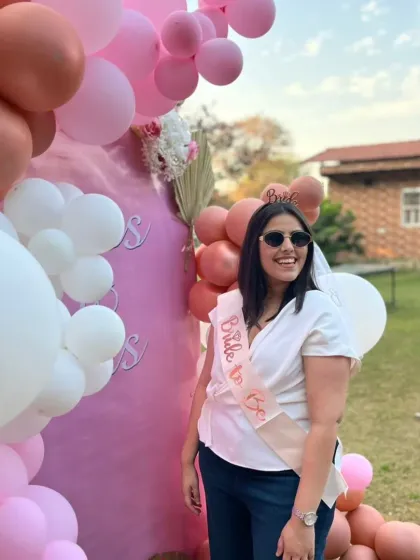 The happy bride-to-be, complete with her sash and tiara, enjoying her special day with the beautiful pink-themed backdrop.