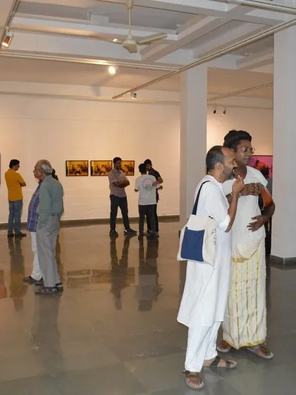 Visitors engaged in conversation while viewing the photographic works.