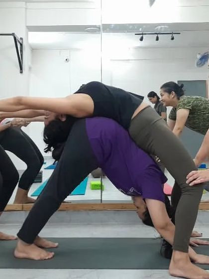 A fun and creative three-person pose, demonstrating the playful and supportive nature of our community practice.