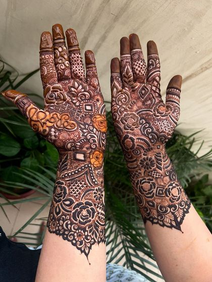 A close-up of the palm side of the heavy henna pattern, showing the personalized initials and shaded flowers.