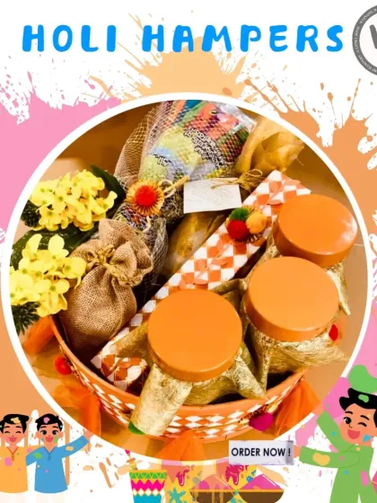 A charming Holi hamper featuring jars of organic colors, a pichkari, and sweet treats in a decorated basket. The orange and yellow theme with floral accents makes it a warm and inviting gift for the festival of colors.