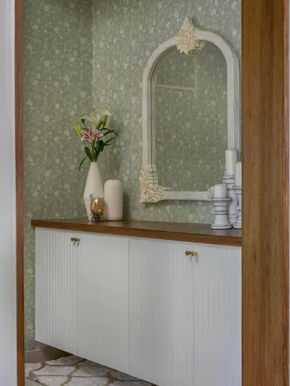 The foyer in 'House of Kismish' exudes Victorian grace with its subtle wallpaper, floating shoe cabinet with fluted doors, and a distressed wall mirror.