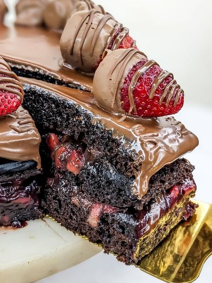 Lifting a slice of our Boozy Nutella Strawberry cake reveals the rum-soaked layers, packed with our homemade strawberry compote.