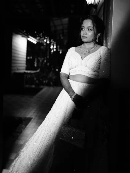 A stunning black and white portrait of a bride in her white reception lehenga, looking chic and modern.