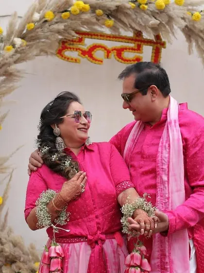 A beautiful portrait of the couple celebrating their 25th anniversary Haldi, posing in front of the custom pampas grass and marigold backdrop we created.