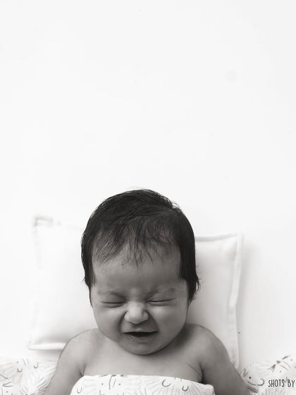 Even a crying face can be a beautiful memory. This black and white portrait captures a raw, real moment of newborn life.