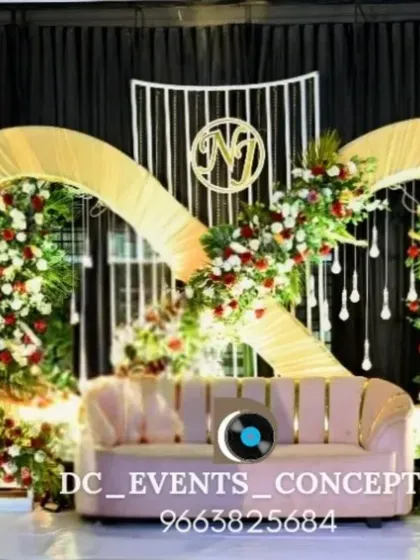 An infinity symbol-inspired backdrop for an engagement, decorated with red and white florals. This unique design includes hanging crystal elements and a custom monogram.