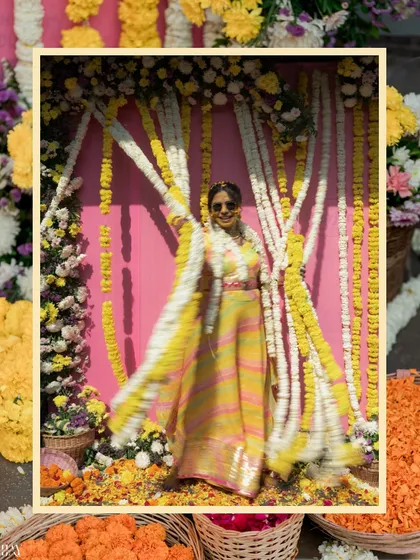 The bride joyfully twirls amidst a shower of flowers, her colorful outfit perfectly matching the festive Haldi decor.