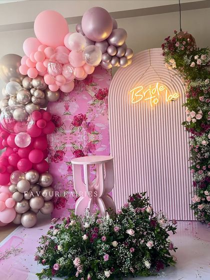 A full view of this stunning pink bridal shower decor. The elaborate balloon garland, floral arrangements, and custom backdrops came together to create an unforgettable celebration space.