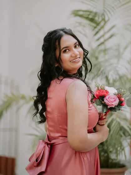 A side profile of a bridesmaid, showcasing her elegant half-up hairstyle and soft, glowing makeup.