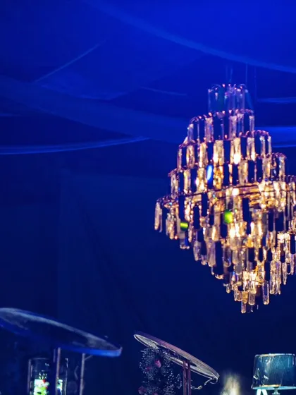 The crystal chandelier appears to float in the deep blue ambiance of the party.