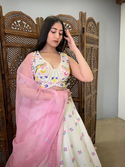 A close-up of the model in the bird-themed lehenga, giving a better look at the intricate and colorful embroidery on the blouse.